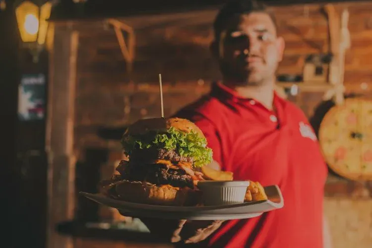 Waiter serving burger in restaurant.