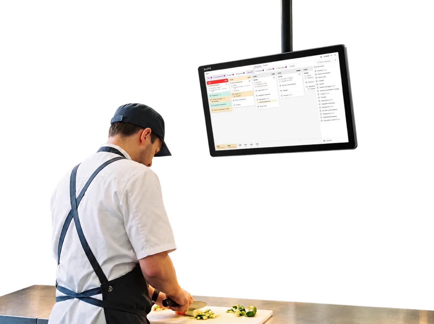 Cook chopping vegetables at a steel kitchen counter under a kitchen display screen
