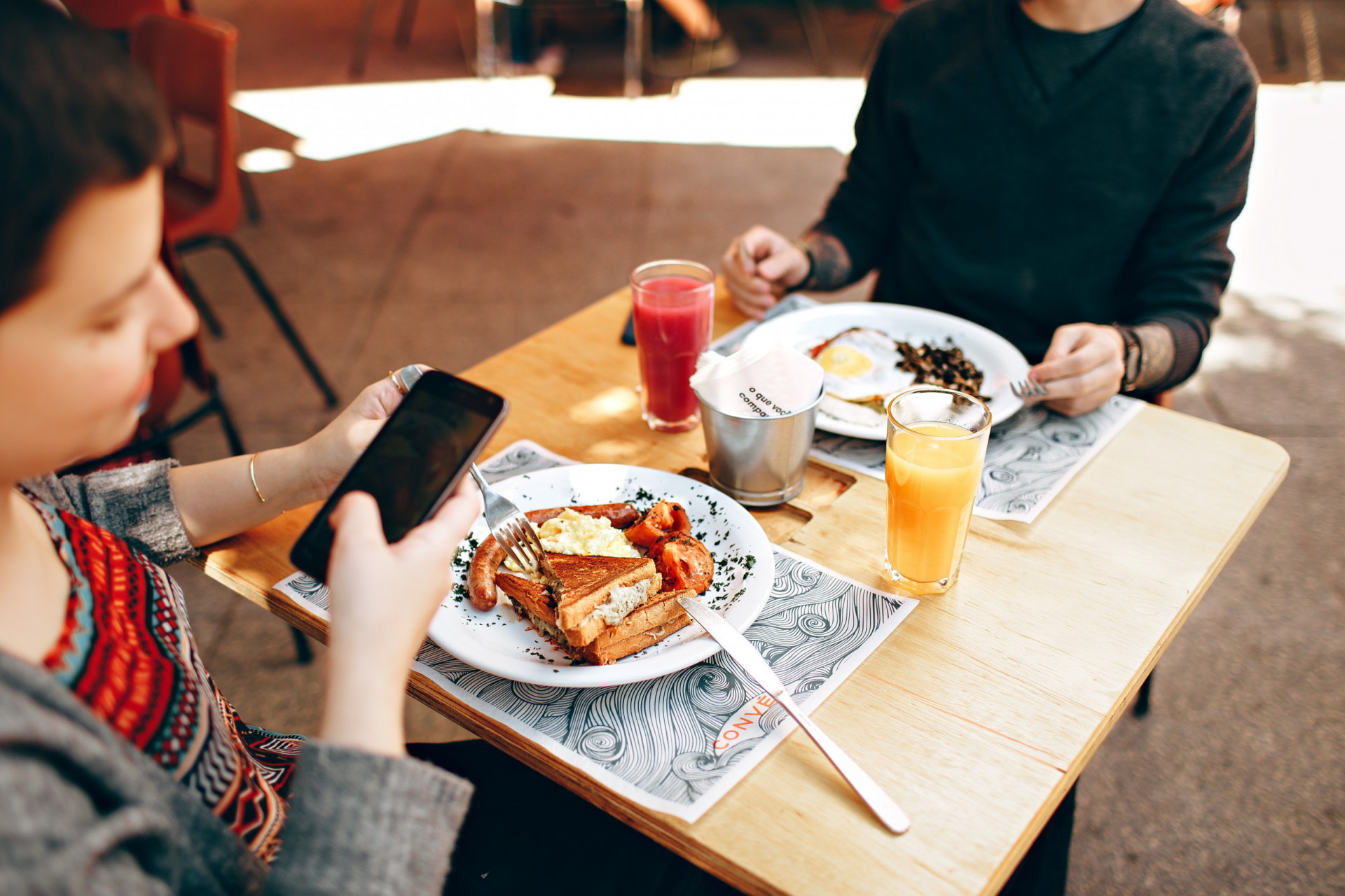People using mobile devices while eating- utilizing customer feedback is a great restaurant marketing idea.