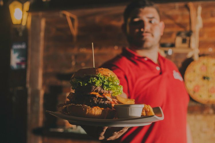 Waiter serving burger in restaurant.